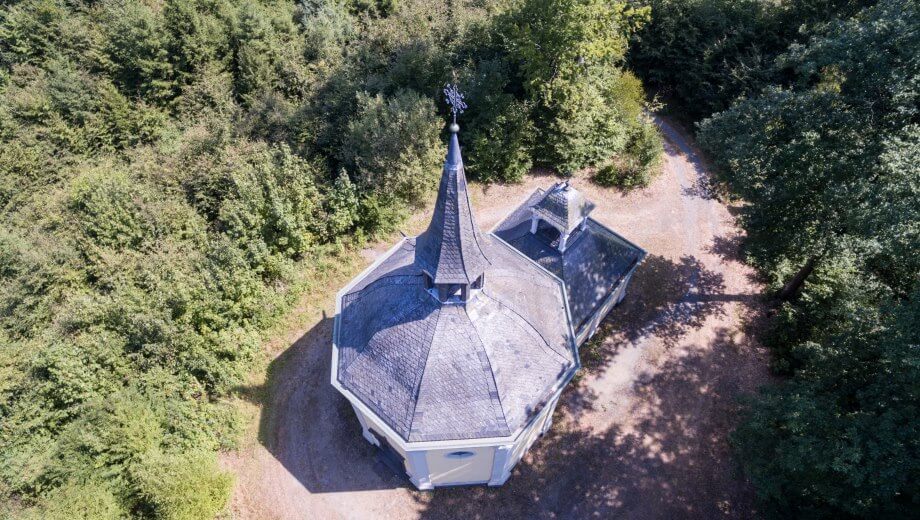 Die historische Heilig Kreuz Kapelle liegt umgeben von Wald.